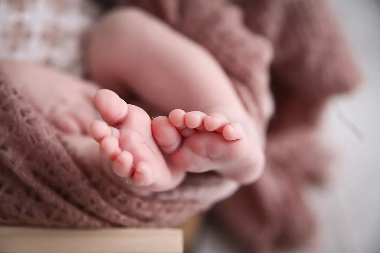 Kleine Babyhand umschließt den Finger eines Elternteils